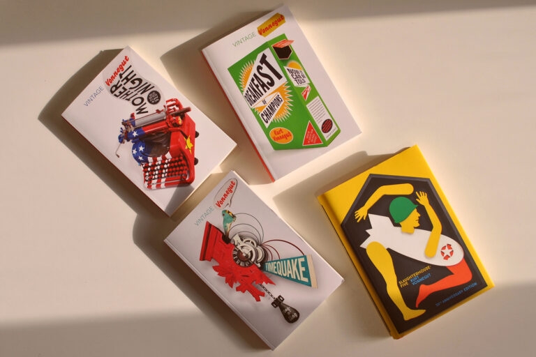 Four books by Kurt Vonnegut on a white table, lit by warm sunlight