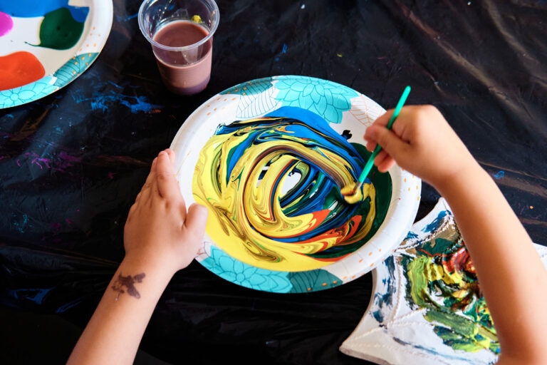 A photo of a child's hands mixing together some paint in a bowl
