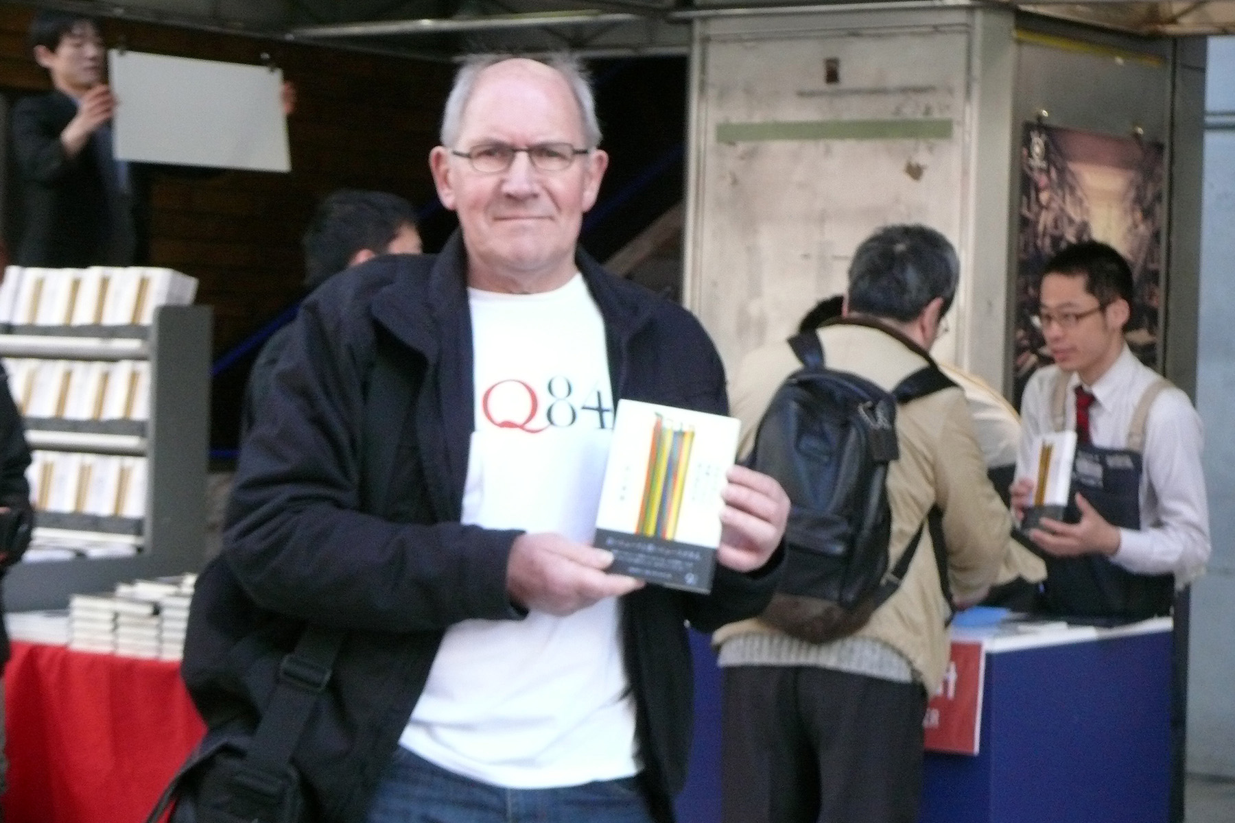 A photo of a fan wearing an 1Q84 T-shirt holding a Japanese copy of Colorless Tsukuru Tazaki  by Haruki Murakami