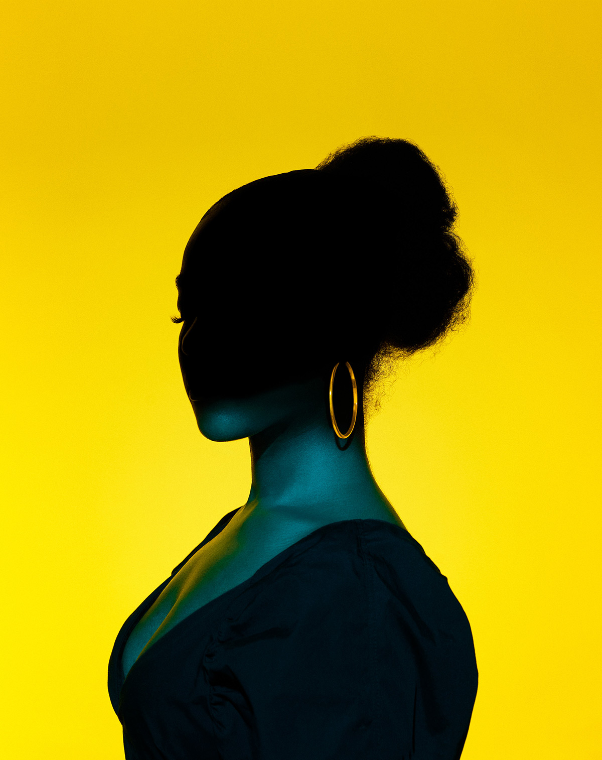 A photo of Keisha the Sket author Jade LB against a yellow backdrop, her face in shadows.