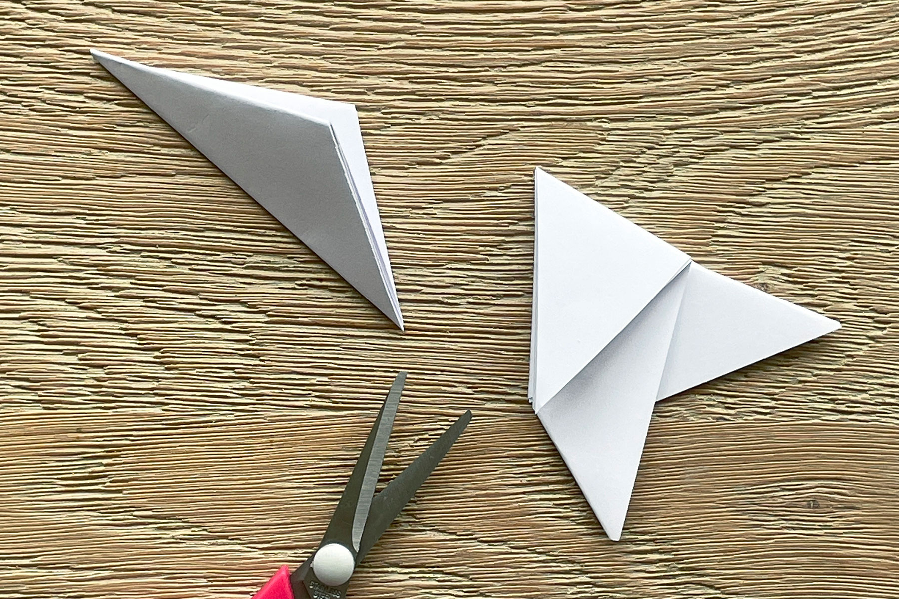 A photo of the folded triangle piece of paper having its bottom cut off