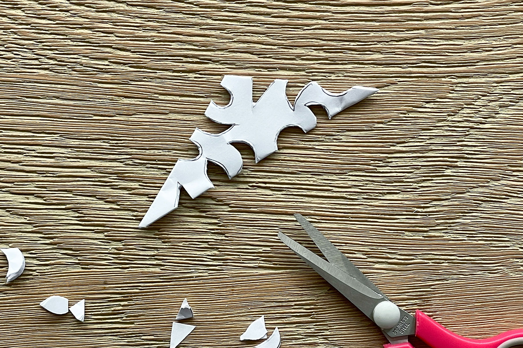 A photo of the triangle piece of paper with little shapes cut out of it with some scissors