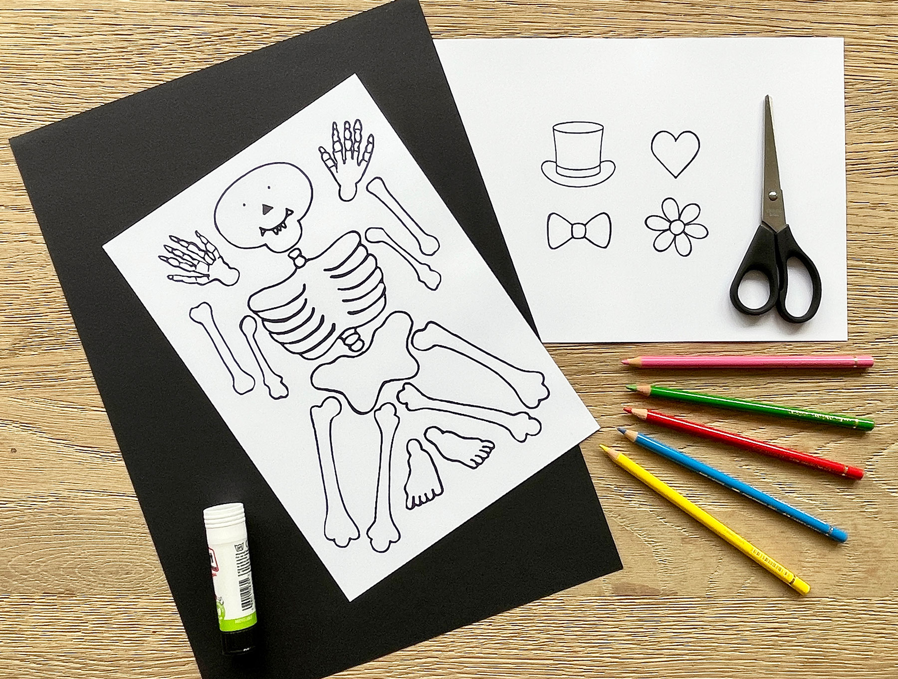 A photo of the materials needed for this craft including, black and white paper, cut out stencils of a Funnybones character and props, colouring pencils, scissors and glue