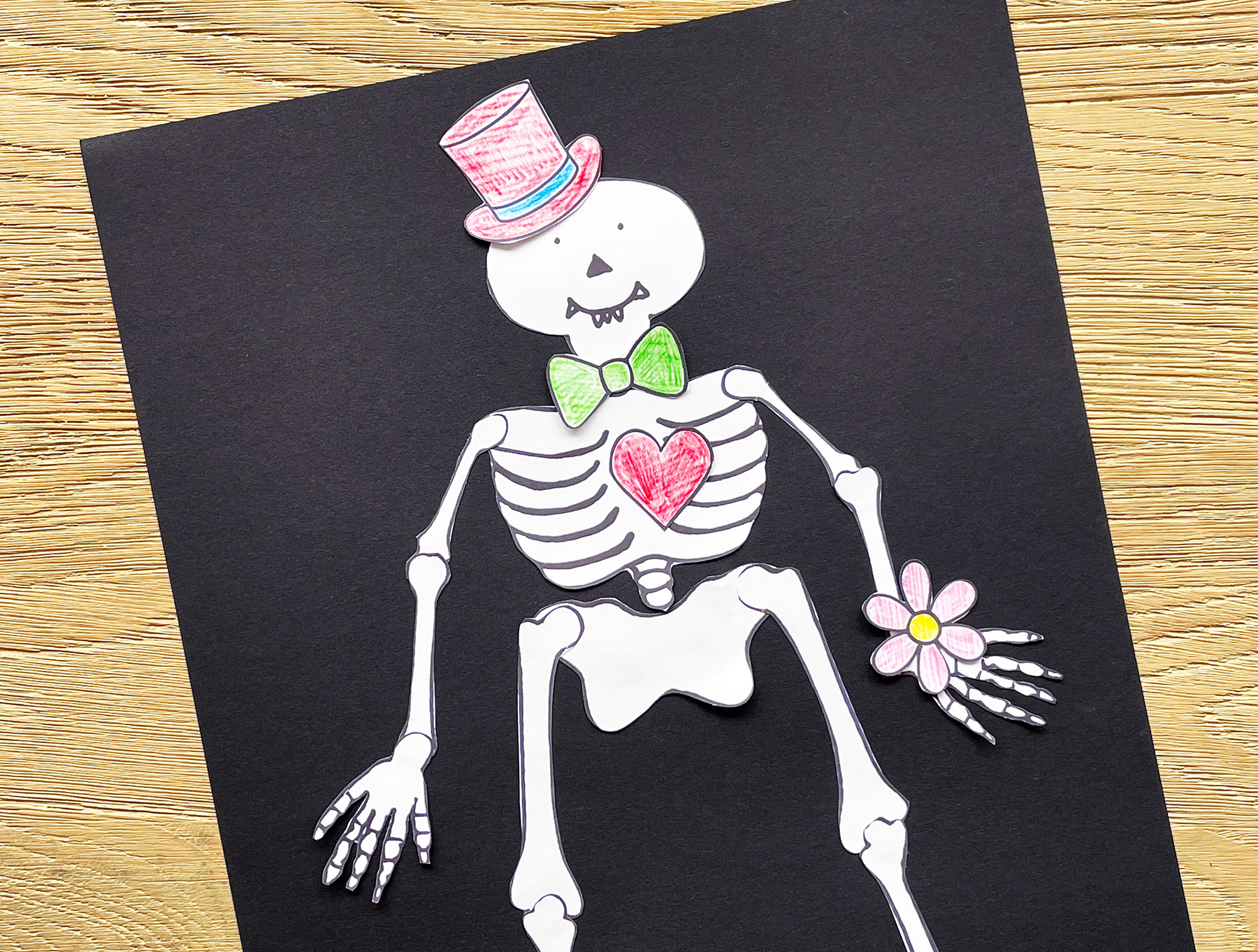 A photo of a cut out Funnybones character on a piece of black paper on top of a wooden table